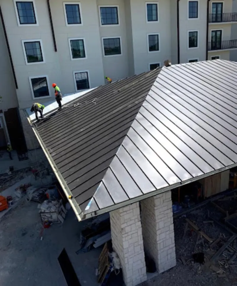 Crew installing standing seam metal roof panels on a commercial project in Hinesville